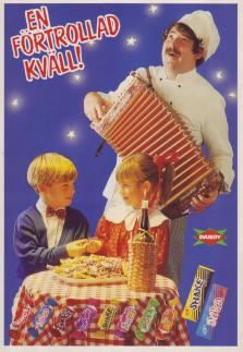 Reklam för Dandy tuggummi där en pojke och en flicka sitter vid ett restaurangbord med en dragspelande kock bredvid sig