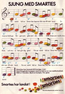 Reklam för Smarties där de små godisbitarna är noter på ett notblad med instruktioner om att sjunga sången