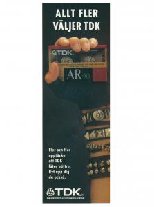 Reklam för TDK kassettband där en armbandsprydd hand håller upp kassettbandet TDK AR 90