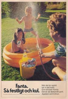 Reklam för drycken Fanta med två barn i en uppblåsbar pool på en gräsmatta där en vuxen person sprutar ner dem med vatten